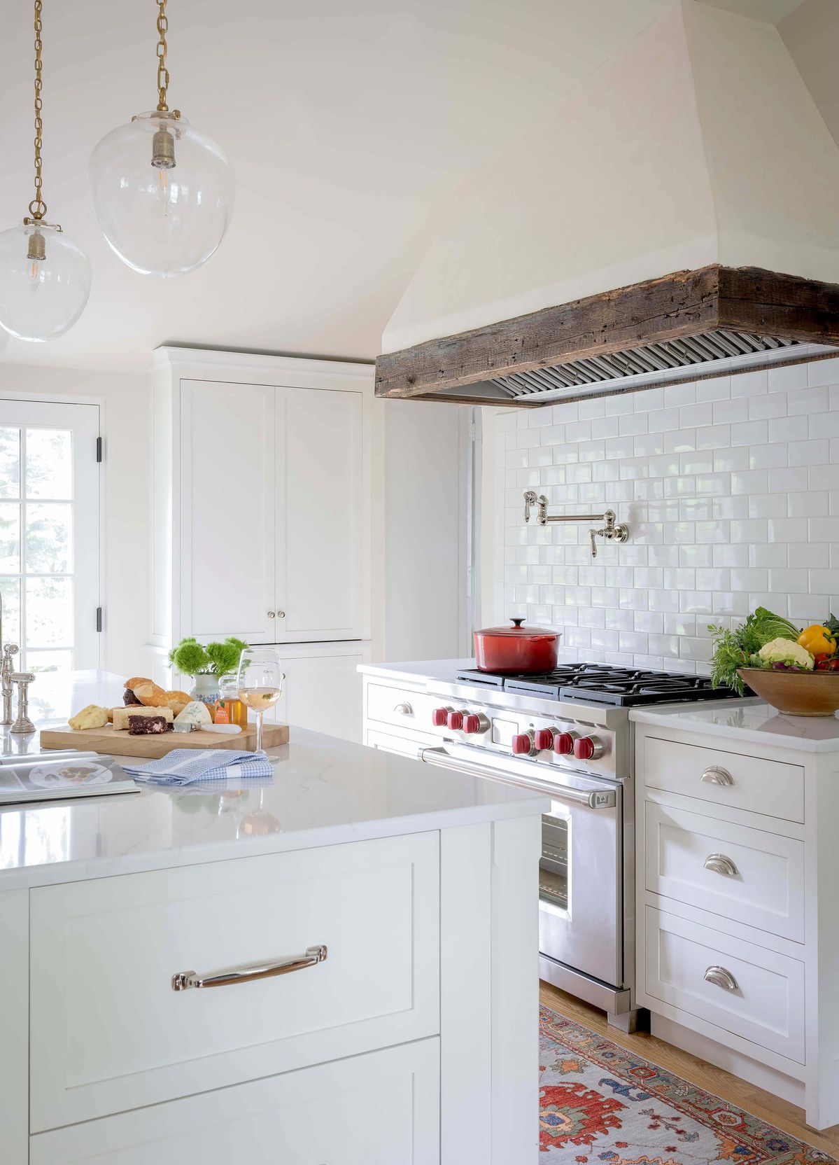 White kitchen with rustic plaster and wood hood