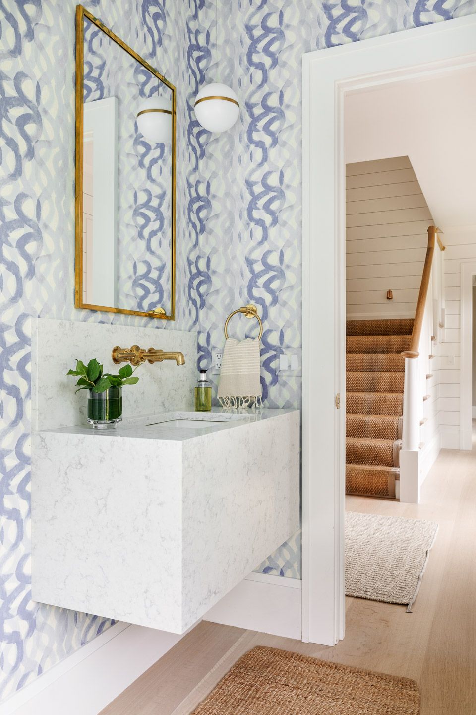 Powder room with wavy blue wallpaper and brass accents