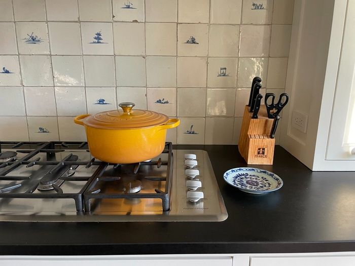 Antique Delft tile behind yellow pot on cooktop