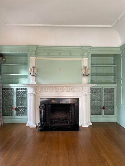 Green bookcase with white fireplace mantel